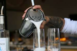 Pouring a classic pisco sour during a Peru cooking vacation.