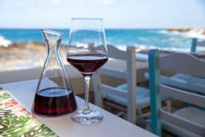 A glass of Cretan wine by the sea during a culinary vacation in Greece.