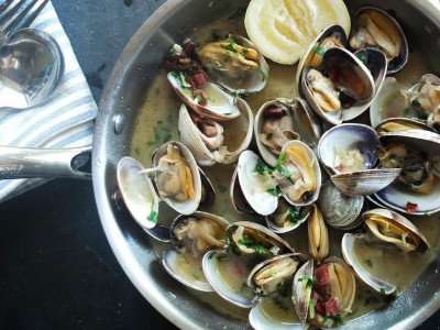 A delicious pan of sauteed clams in wine sauce during a culinary vacation in Italy.