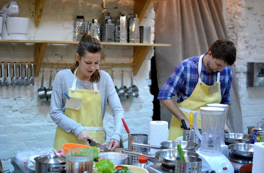 A pair of travelers enjoying a hands-on cooking class.