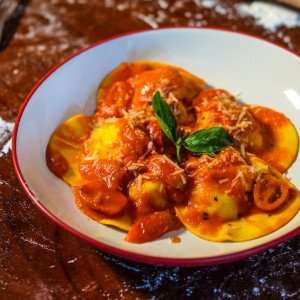 A plate of ravioli with a fresh tomato sauce.