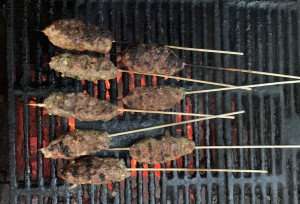 Lamb kofta kebabs roasting over a charcoal fire.