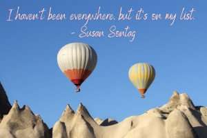 Inspirational travel quote by Susan Sontag over a picture of balloons flying over Cappadocia.