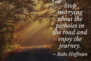 An inspirational quote with an image of a road in the middle of a forest in autumn.