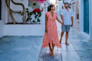 A couple enjoying a romantic stroll during a culinary vacation on a Greek Island.