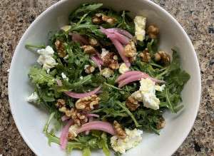 A tasty arugula salad with pickled onions and walnuts.
