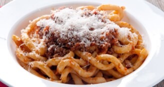 Pici pasta with ragu and parmesan cheese.